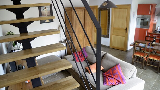 Un interior moderno con una escalera, un sofá con cojines y un área de comedor.