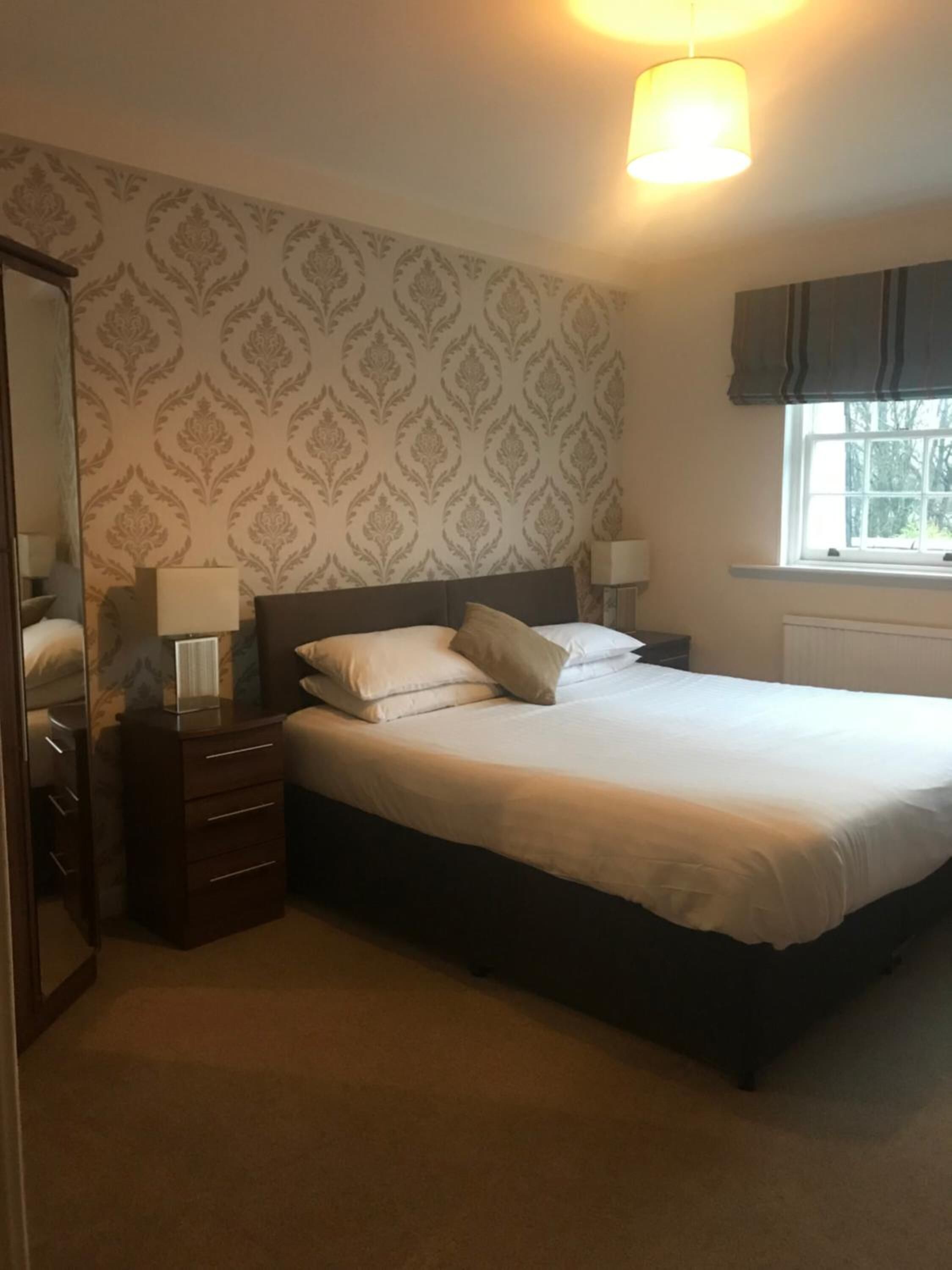 A neatly arranged bedroom with a bed, dresser, and bedside lamps.