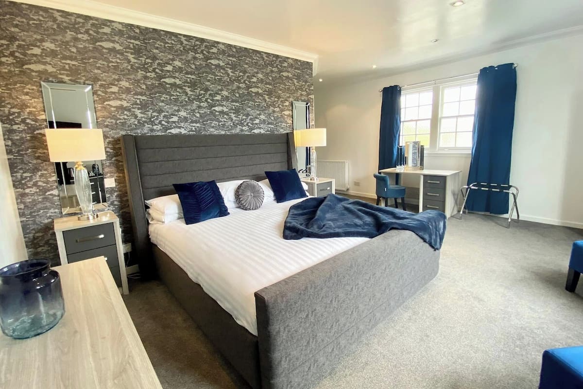 A modern hotel room with a large bed, a desk, and a chair.