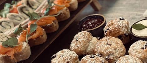 A variety of pastries and desserts on display, including scones, sandwiches, and pastries with various toppings and fillings.