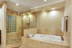 A modern bathroom with a glass-enclosed shower, a large bathtub, and a mirror.