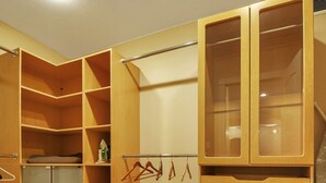 A walk-in closet with multiple shelves and drawers, a hanging rod, and a small refrigerator.