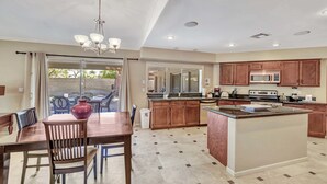 A spacious kitchen with wooden cabinets, a central island, and a dining area with a table and chairs.