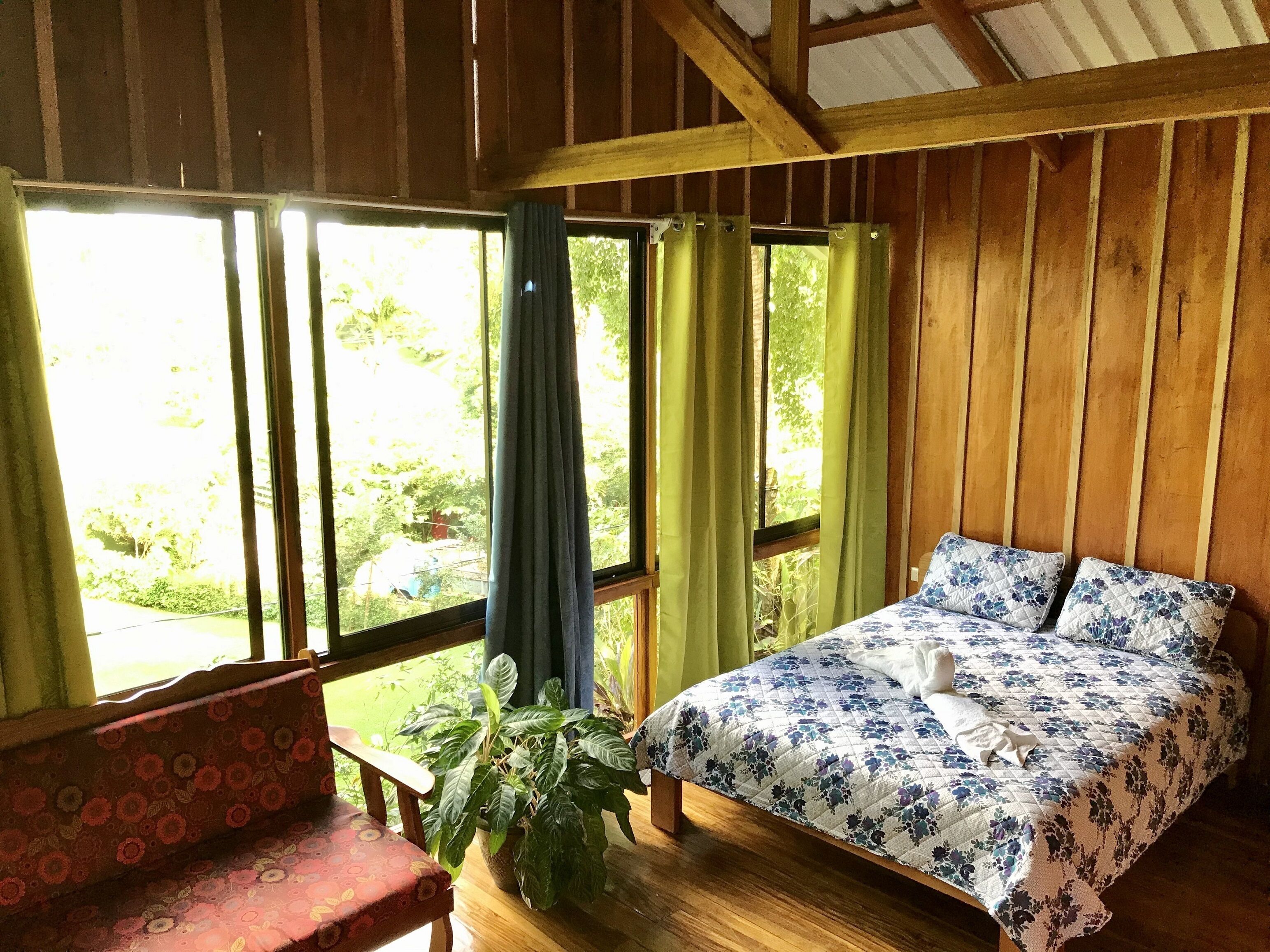 Une pièce en bois avec un lit, un banc et une fenêtre avec des rideaux.