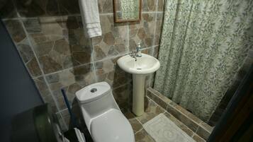 Een badkamer met toilet, wastafel en douchegordijn.