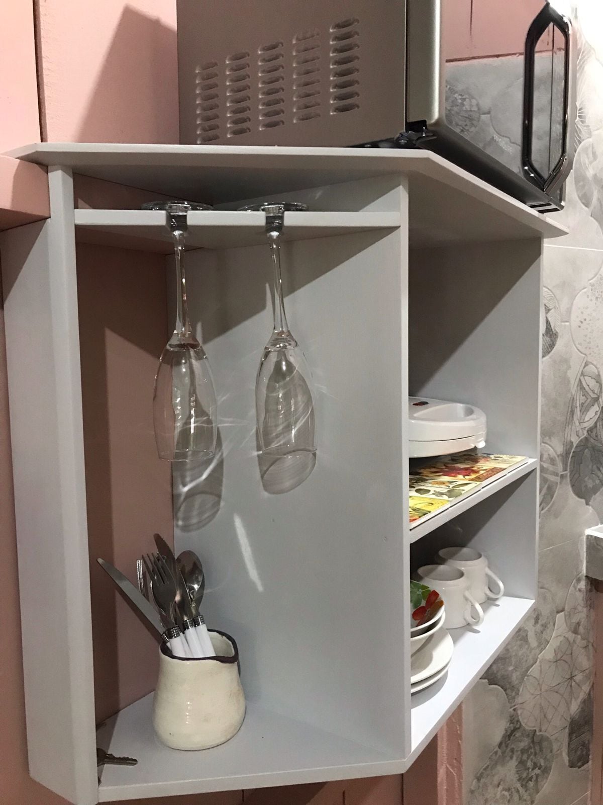 Eine Küche mit einem weißen Schrank, einer Weinregalanlage und einer Kaffeemaschine.
