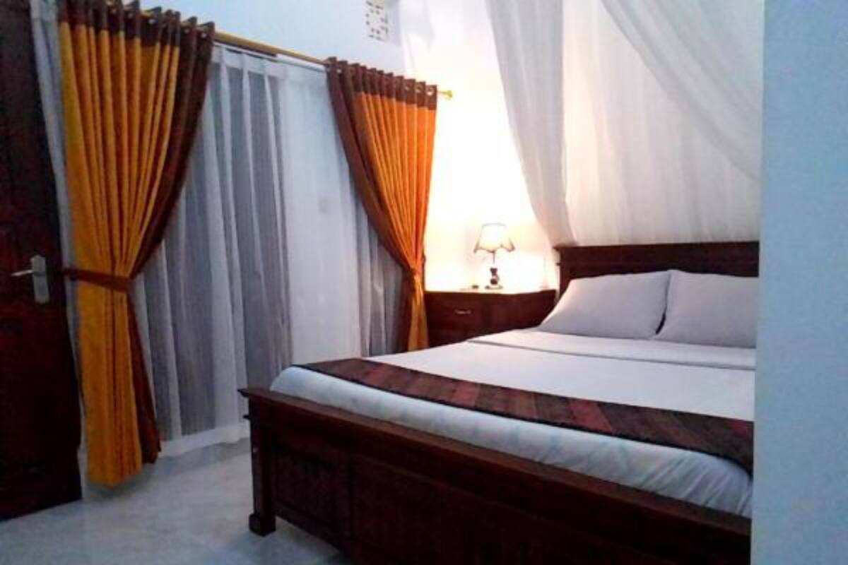 Une chambre à coucher avec un lit, des rideaux, une table de chevet et une lampe.