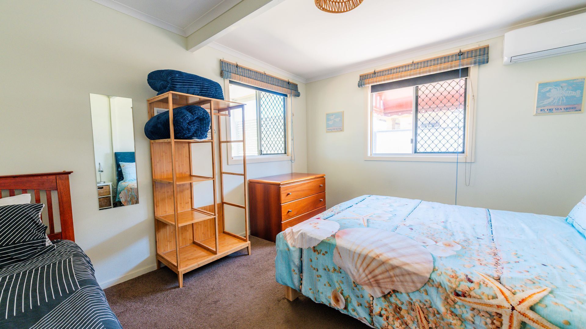Een slaapkamer met een bed, een houten garderobe, een dressoir, een spiegel en een raam met uitzicht.