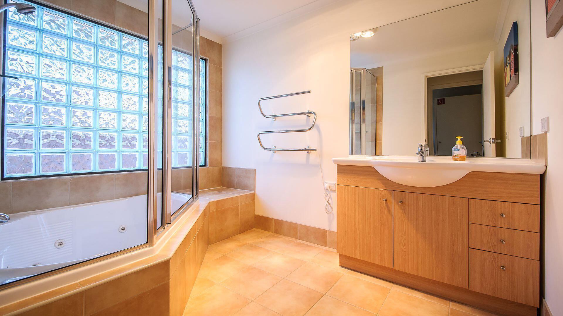 Une salle de bain moderne avec une douche à parois de verre, un meuble-lavabo en bois avec un miroir et un sol carrelé.
