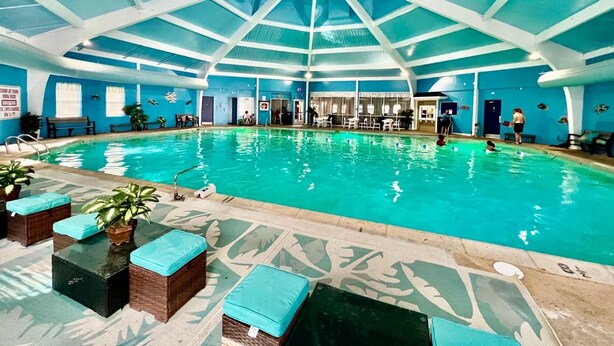 An indoor swimming pool with a high ceiling and blue walls. - Private 5BR Escape with Hot Tub & Games, Near Lakes, Hikes & Water Parks (Long Pond)