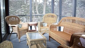 A wicker-furnished outdoor seating area with a view of snow-covered trees. - Private 5BR Escape with Hot Tub & Games, Near Lakes, Hikes & Water Parks (Long Pond)