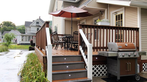 Une terrasse en bois équipée d’un barbecue, de mobilier d’extérieur et d’un espace patio couvert.