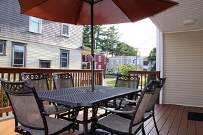 Un patio techado con mesa y sillas, con vista a un barrio residencial.