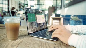 Un ordinateur portable sur une table, avec un calendrier et un verre de café glacé.