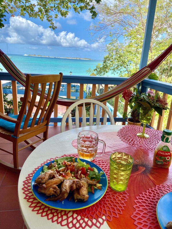 A table with a plate of grilled chicken, a glass of beer, and a bottle of Italian dressing.