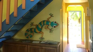 A staircase with blue and orange railings leading to a landing with a wooden cabinet and a lizard decoration. - Just in-November dates have just become available  (L’Esterre)