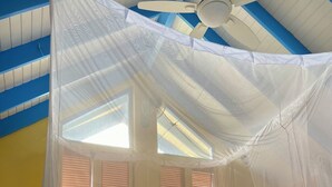 A bed with a canopy, a ceiling fan, and windows with blinds. - Just in-November dates have just become available  (L’Esterre)