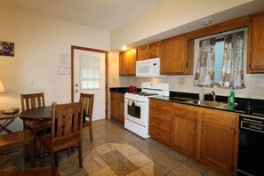 A compact kitchen with wooden cabinets, a stove, a microwave, and a sink.