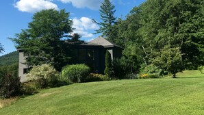 A house surrounded by a well-maintained lawn and trees, with a clear blue sky above. - Private Suite with a Sweet View. Spacious, close to town, dog friendly (Shelburne Falls)