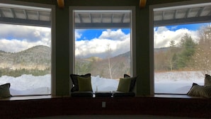 A room with a large window overlooking a snowy landscape and mountains. There are two chairs with cushions. - Private Suite with a Sweet View. Spacious, close to town, dog friendly (Shelburne Falls)
