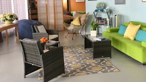 A cozy living room with a green sofa, wicker chairs, a coffee table, and a patterned rug. - Private Suite with a Sweet View. Spacious, close to town, dog friendly (Shelburne Falls)