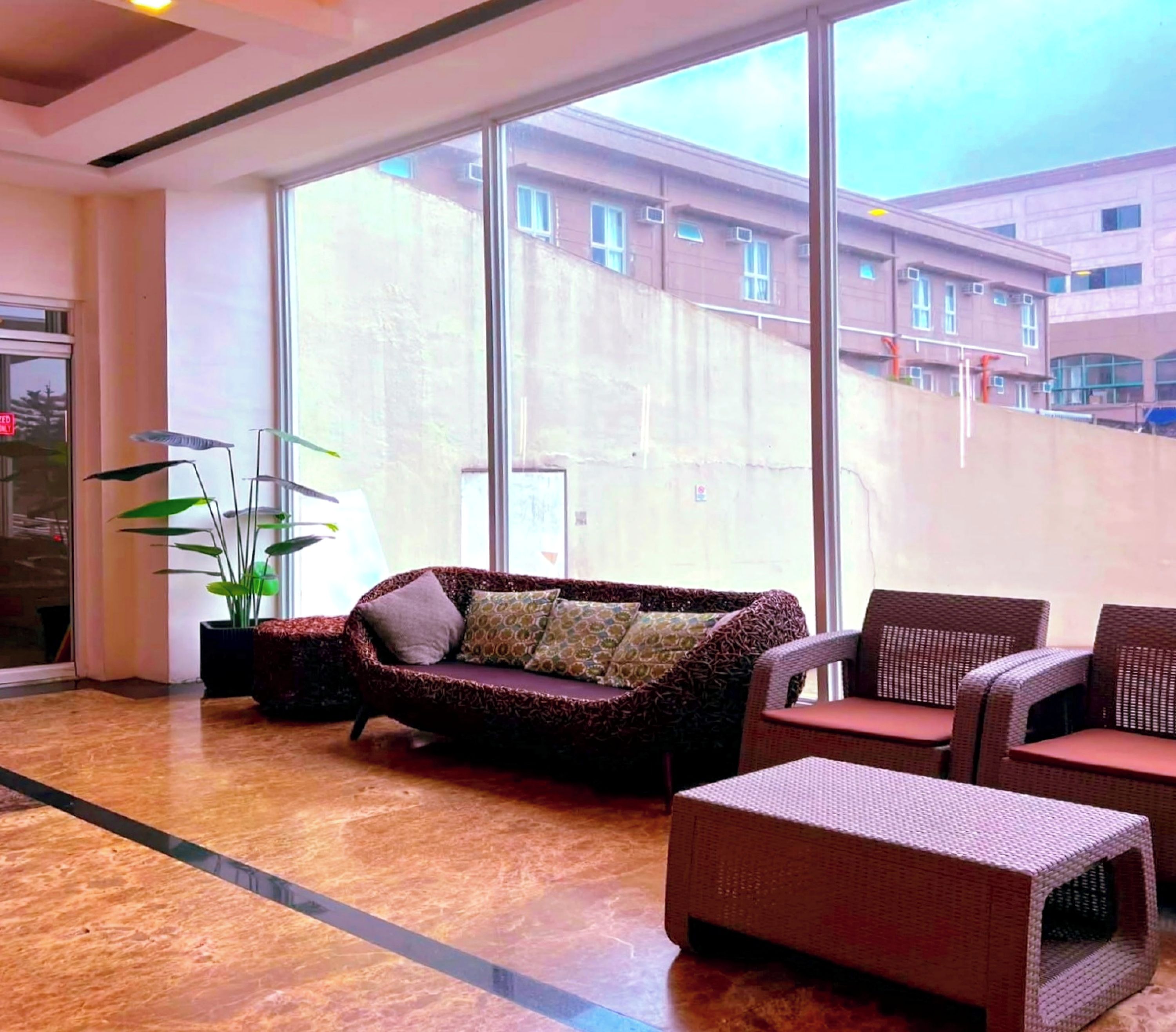 A spacious lobby with a large window, a sofa, and wicker furniture.