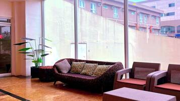 A spacious lobby with a large window, a sofa, and wicker furniture.
