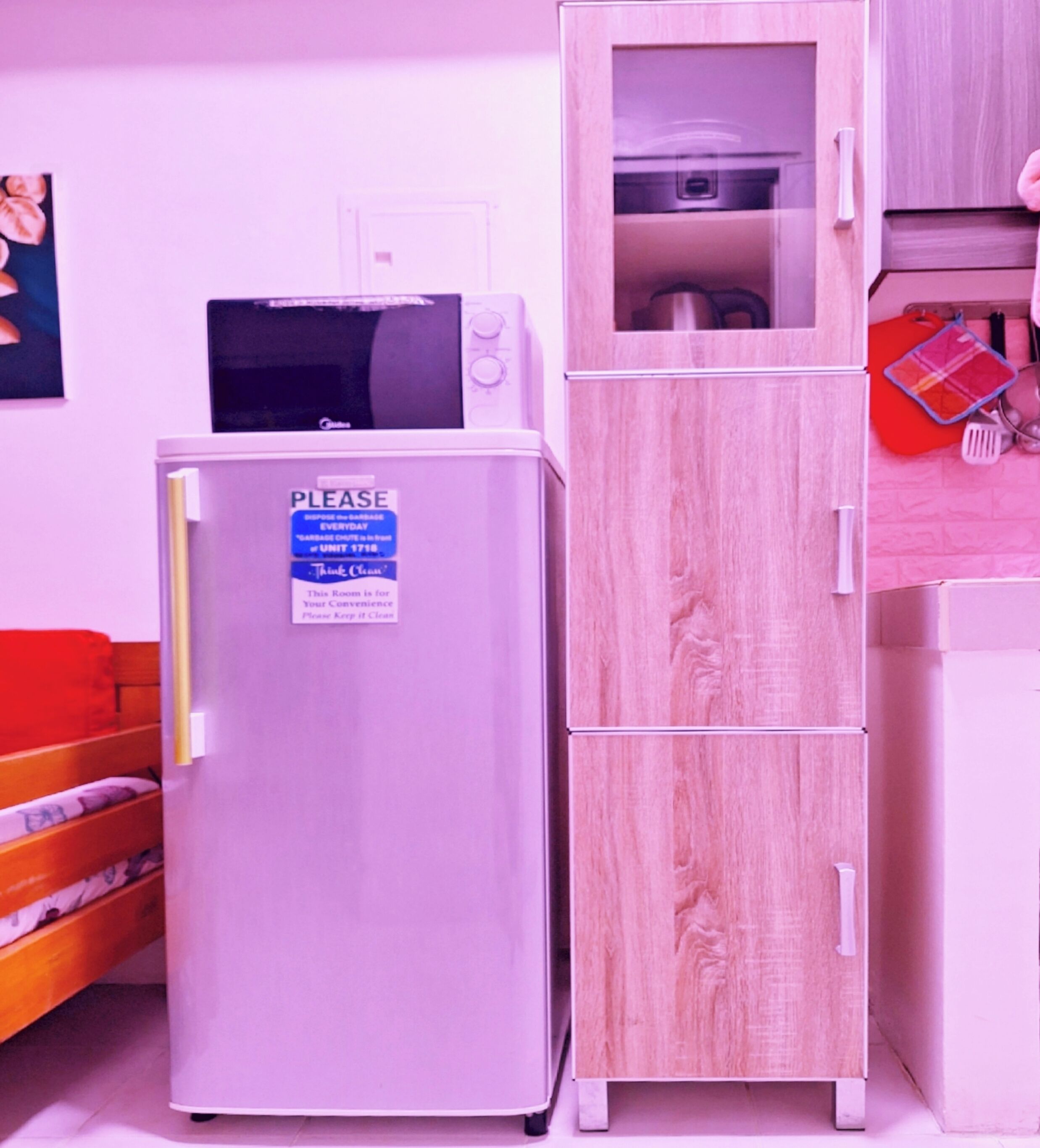 Eine Küchenzeile mit einer Mikrowelle, einem Kühlschrank und einem Holzkorpus.