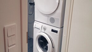 A compact laundry room with a front-loading washer and dryer stacked on top of each other. - The cosmopolitan apartment (Turku)