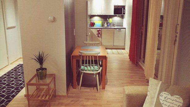A compact living space with a dining area, kitchenette, and a small seating area with a cushion. - The cosmopolitan apartment (Turku)