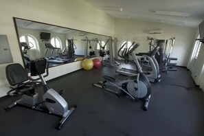 Une salle de sport équipée de matériel d’exercice, d’un grand miroir et de ballons de gymnastique.