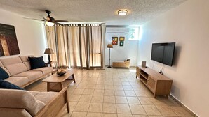 Un salon comprenant un canapé, une table basse, un téléviseur et un ventilateur de plafond.