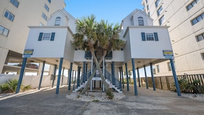A hotel with a central staircase flanked by two buildings, each with a sign indicating rental availability.