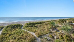 A coastal landscape with a beach, vegetation, and a clear sky.