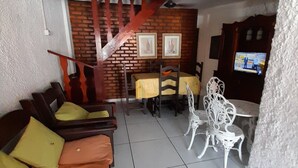 Un salon avec un canapé, des fauteuils, une table et un téléviseur.