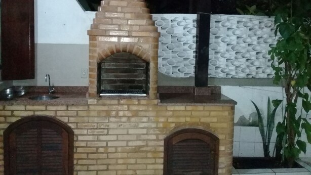 Une cuisine équipée d’un four en briques, d’un évier et d’un mur décoratif.