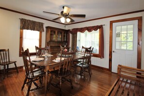 A dining room with a wooden table set for six, surrounded by six chairs.