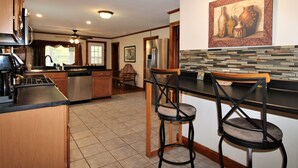 Una cocina moderna con una isla central, taburetes de bar y un refrigerador.