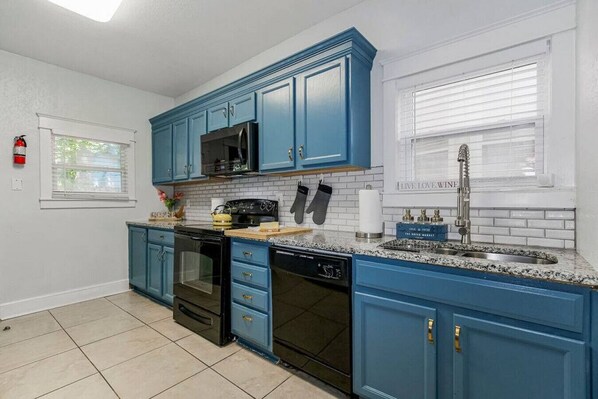 A kitchen with blue cabinets, a microwave, a stove, and a dishwasher.