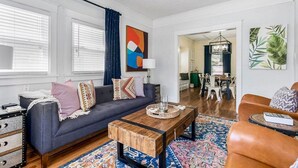 Una sala de estar moderna con un sofá azul oscuro, una mesa de centro de madera y un tapete estampado.
