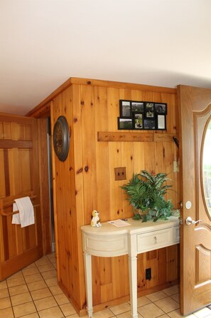 A wooden-paneled bathroom with a white vanity, a clock, and a potted plant. - Cooperstown Baseball Rentals - Anglewoods (Maryland)