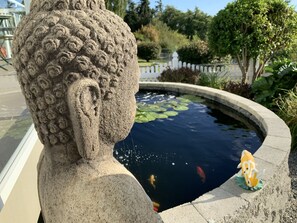 Una escultura de piedra con un estanque, peces y una figura decorativa de pez.