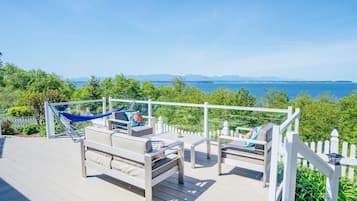 A deck with outdoor seating and a view of the sea.