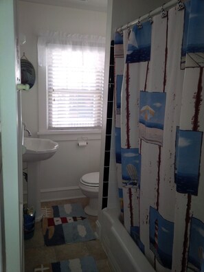 Een bad/douchecombinatie, toiletpapier