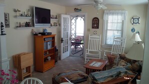 Ein gemütliches Wohnzimmer mit Fernseher, Holzmöbeln und maritimer Dekoration.