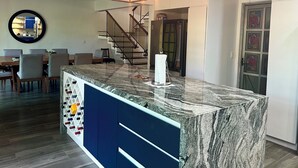 A modern kitchen with a marble island, a staircase, and a dining area. - Cancun - Soho (Cancun)