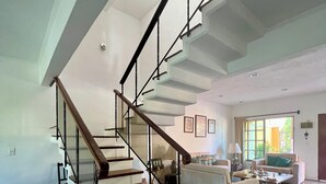 A spacious living area with a modern staircase, a sofa set, and a coffee table. - Cancun - Soho (Cancun)
