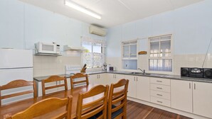 A kitchen with white cabinets, a microwave, a stove, a sink, and a dining table with chairs.