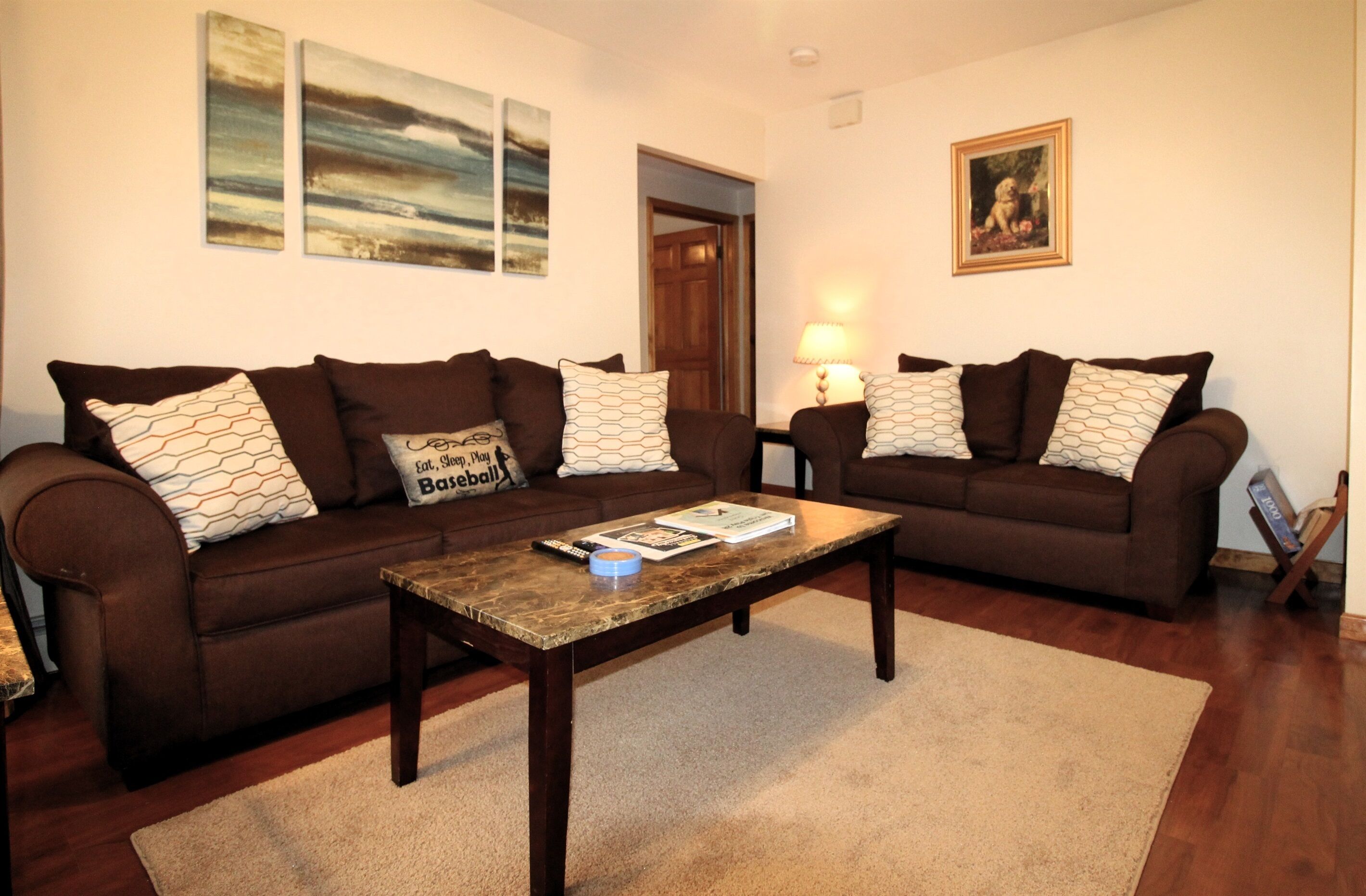Ein Wohnzimmer mit zwei braunen Sofas, einem Holztisch und einem Teppich.
