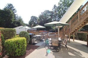An outdoor patio with tables and chairs, covered by umbrellas, and a wooden staircase. - Cooperstown Baseball Rentals - Elm-Triple Play #2R (Oneonta)